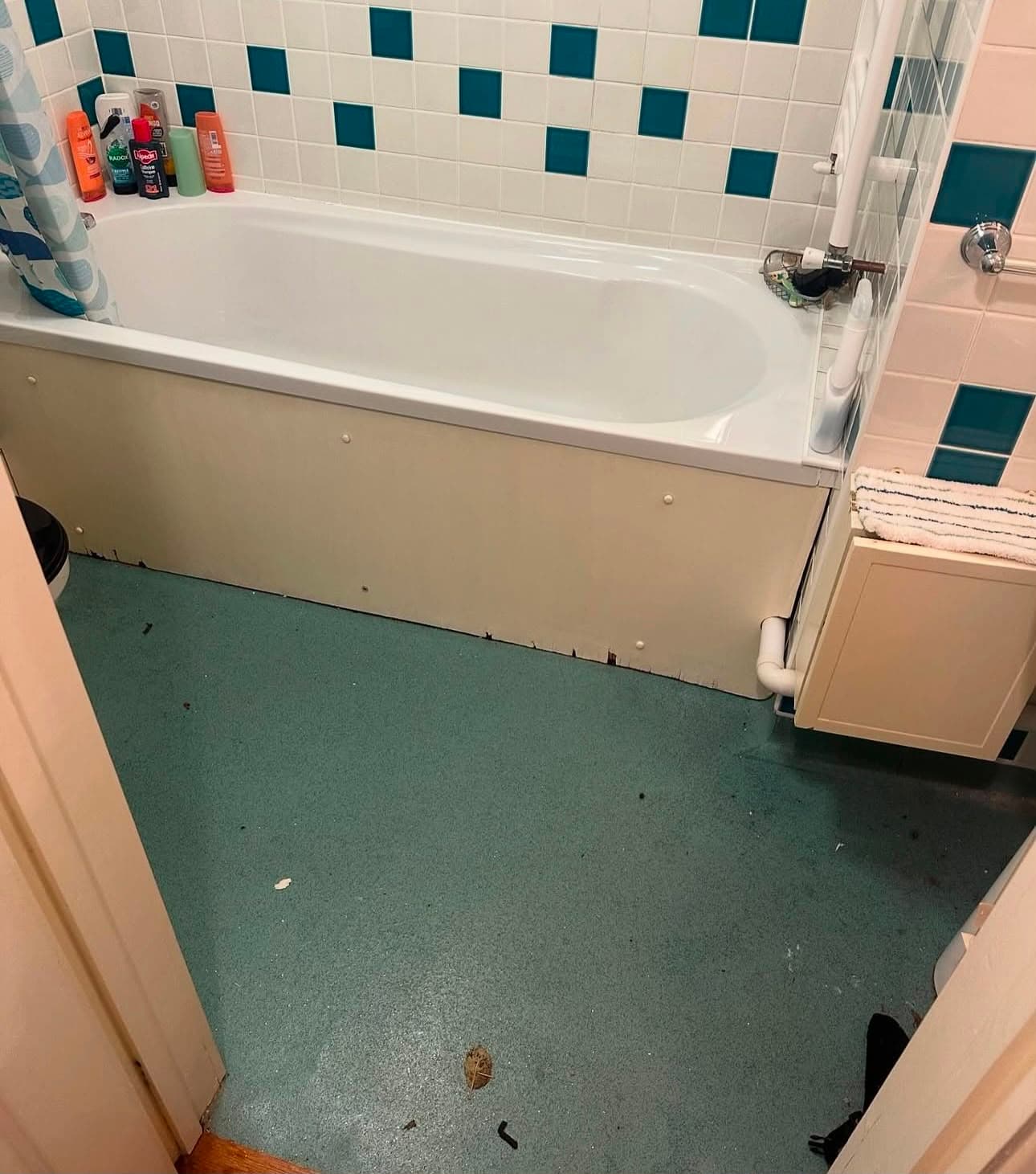 Before — a bathroom floor with debris and marks around the bath panel