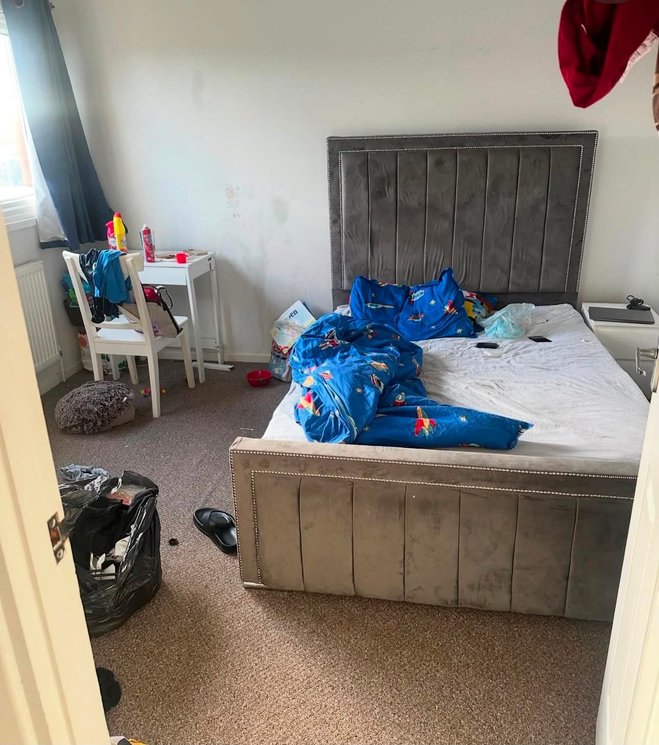Before — a child's bedroom with bedding, clothes and rubbish across the floor
