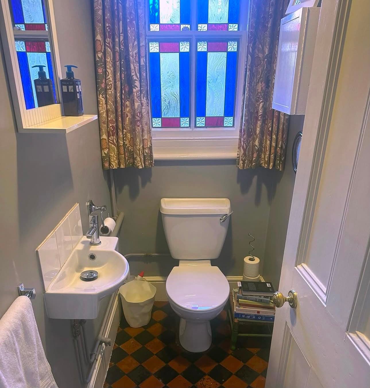 a small cloakroom with a stained-glass window and tiled floor